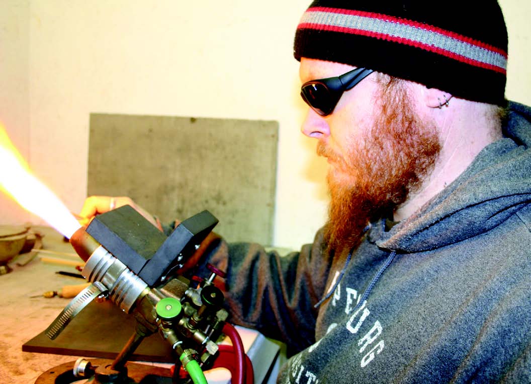 Artist works with glass in a flame.