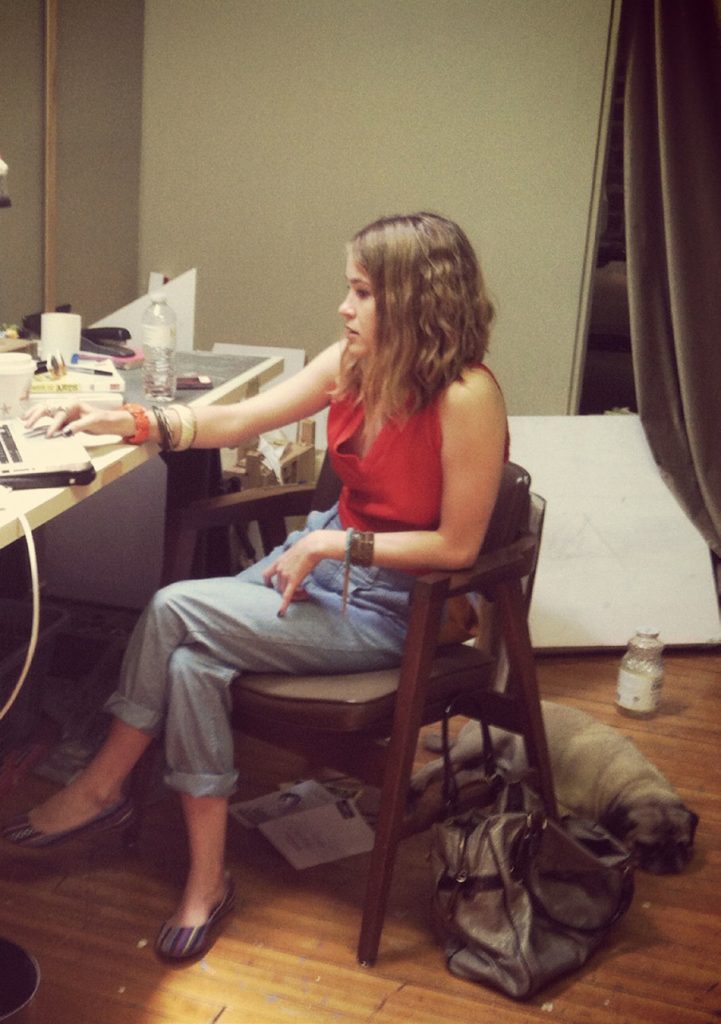 Female artist sits at her desk working.